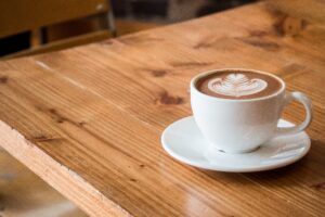 A cup of coffee sits on a wooden table