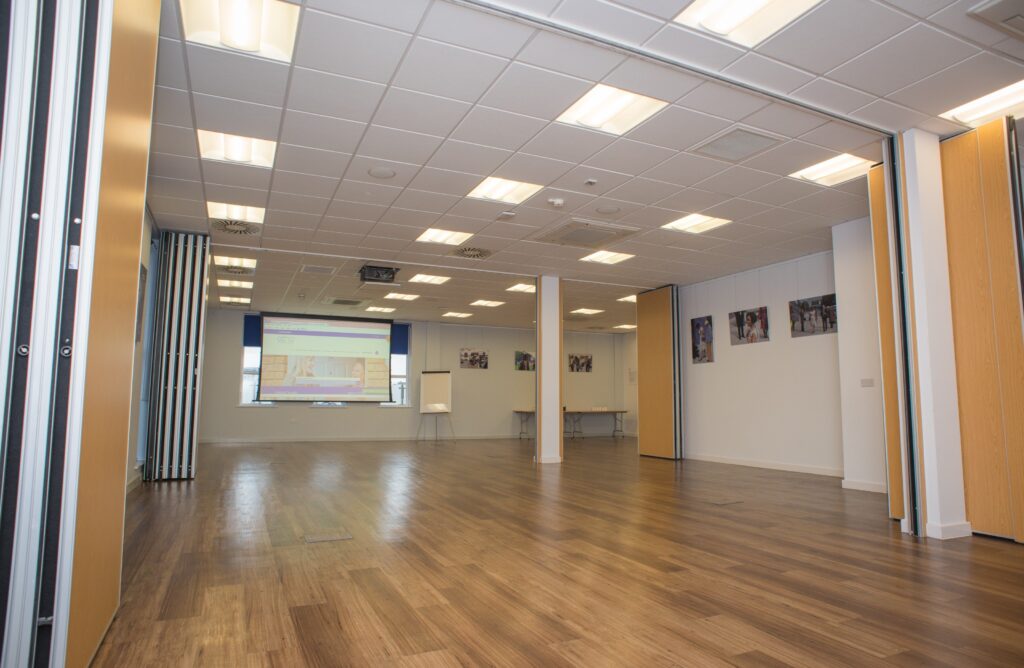 An empty room with a projector on at the far end