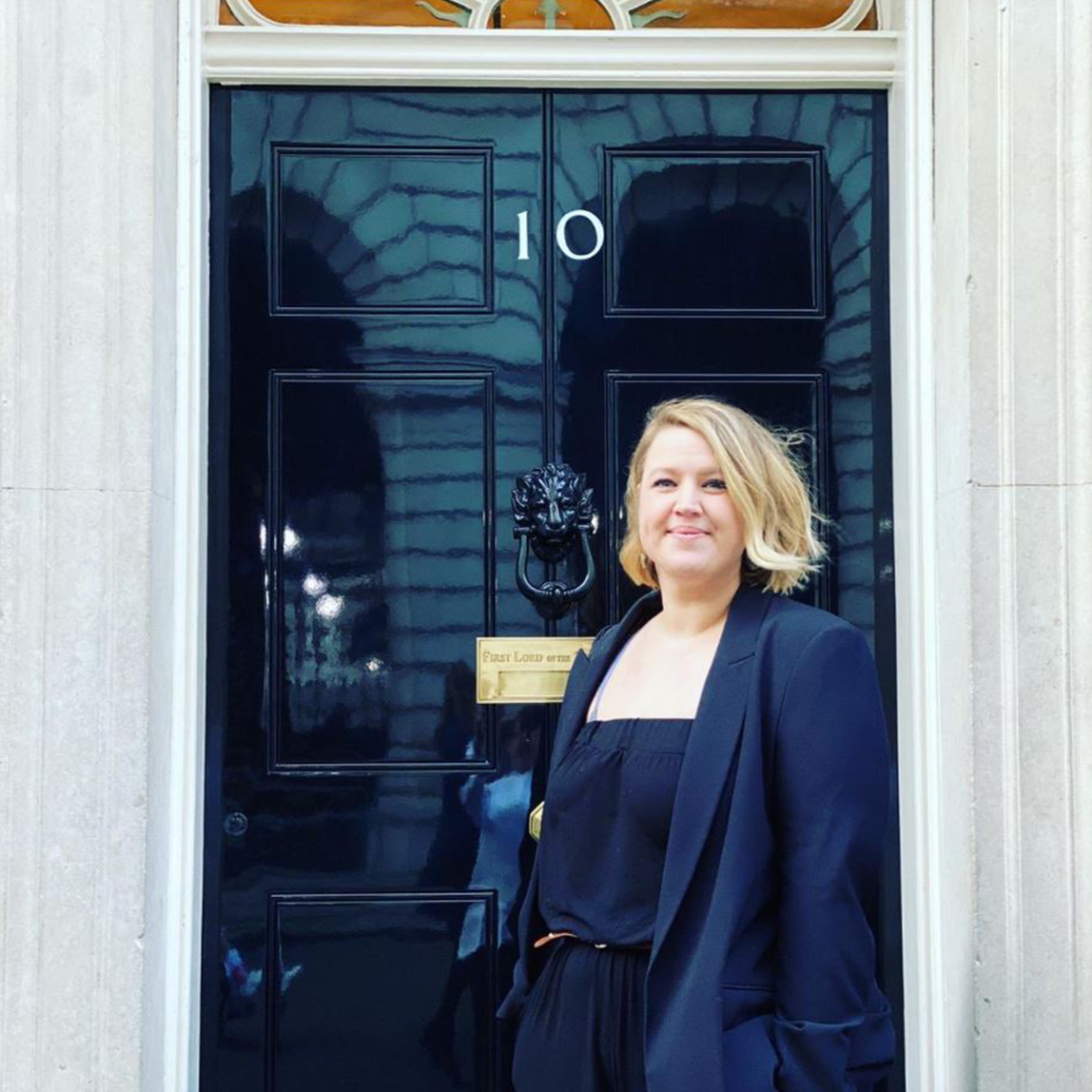 Woman with blonde hair standing outside the door of number 10 Downing Street