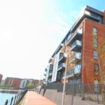 A block of flats overlooking the river and set against a sunny blue sky